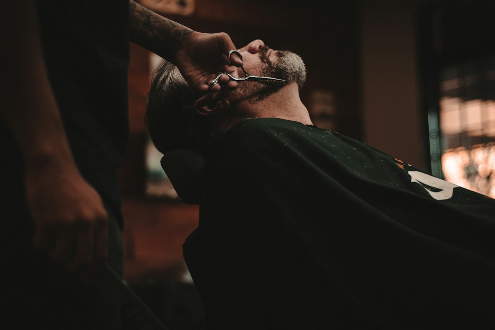 Barbero realizando perfilado de precisión en línea de patilla y contorno facial